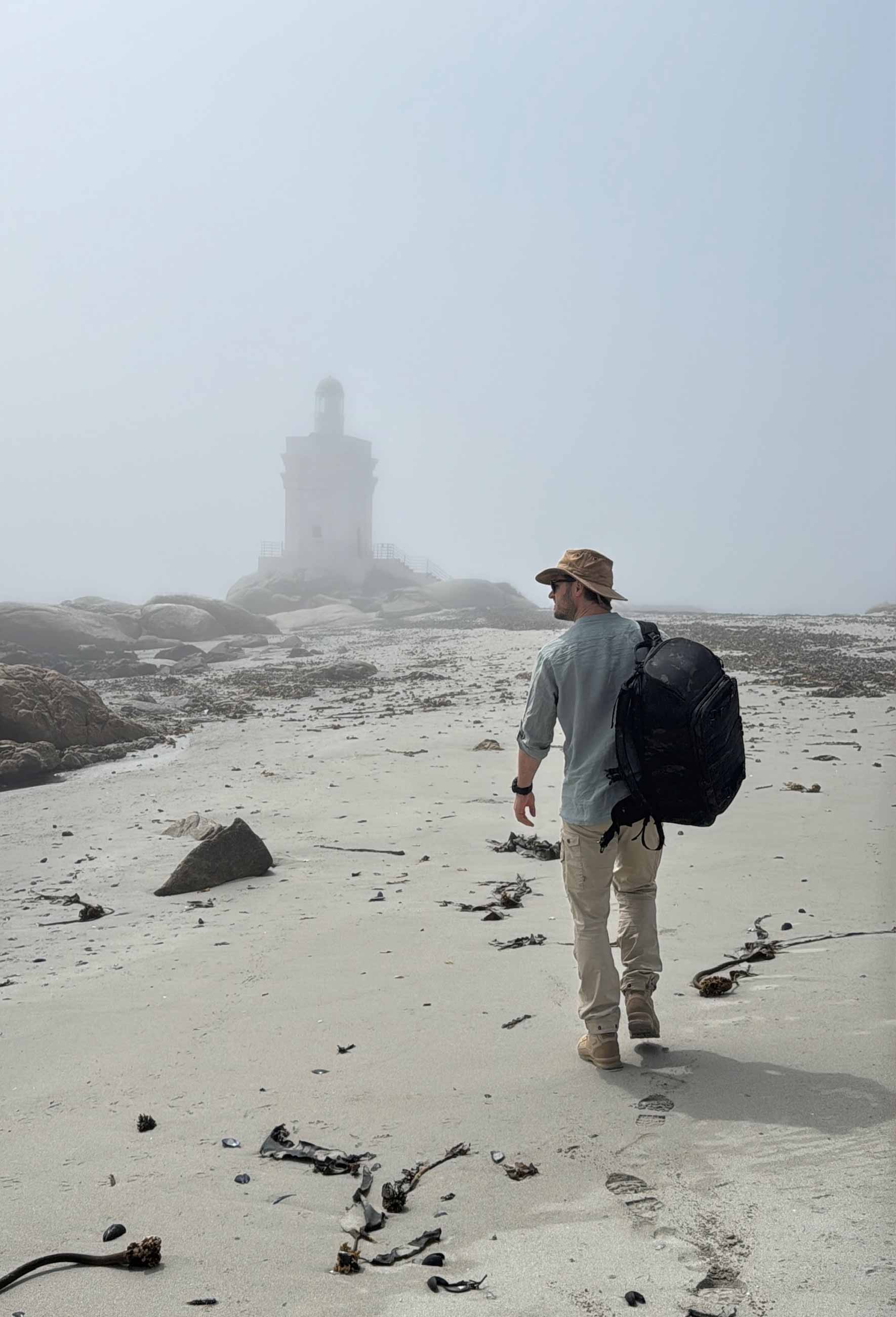 Alex Volz mit Rucksack auf Sandboden mit Blick auf einen Turm